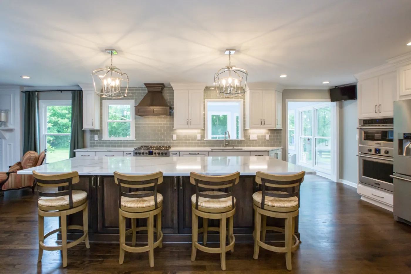 A remodeled kitchen with white cabinetry, a walnut island and sage tile backsplash