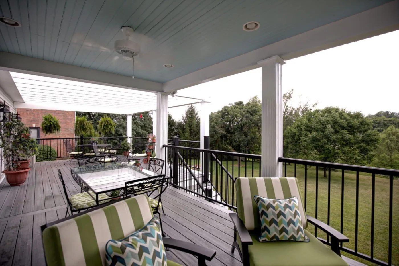 A covered rear porch with a painted bead board ceiling overlooking a lawn