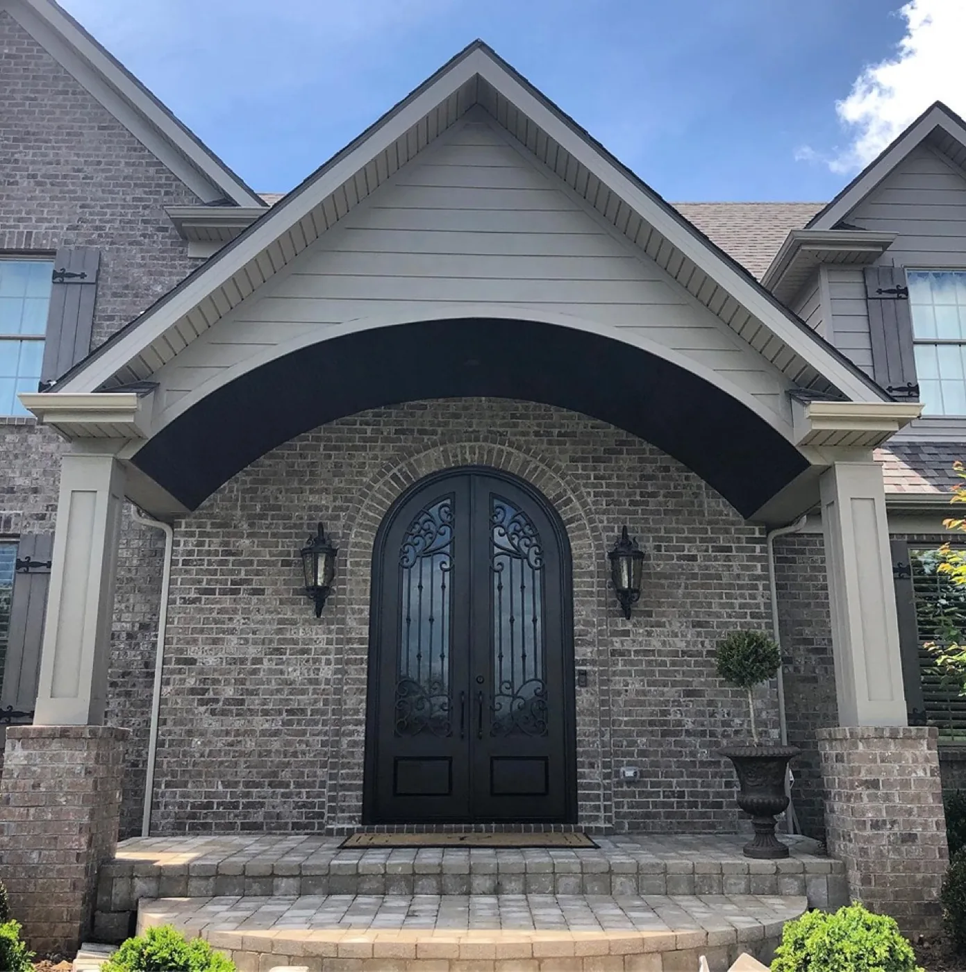 A brick front entry with an arched portico, stone steps and iron doors
